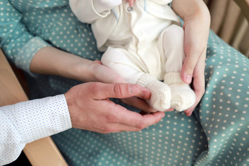 Parents holding in the hands feet of newborn baby boy. Happy Family concept.