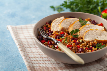Trendy lunch with cereal, beetroot and chicken. Served in a bowl on a blue painted background. Front view.