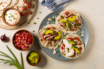 Mini tortillas with tomato salsa, avocado and boiled chicken. Top view.