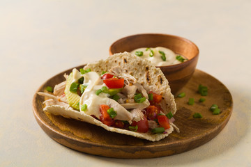Mini tortillas with tomato salsa, avocado and boiled chicken. Front view.
