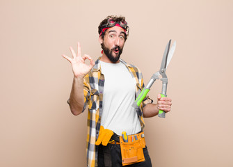 young man housekeeper with a scissors against flat wall