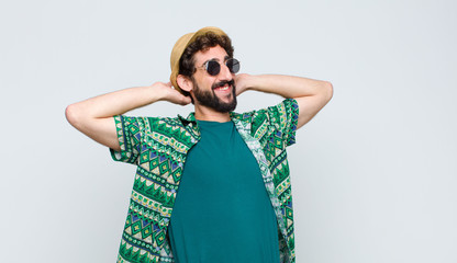 young tourist man smiling and feeling relaxed, satisfied and carefree, laughing positively and...