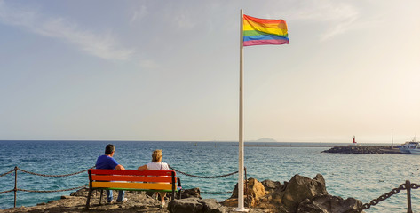 Día del Orgullo. Pareja sentada relajadamente en un banco mirando al mar. Rincón del orgullo en...