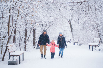 Fototapeta na wymiar Father and mother with daughter walk in a snowy park