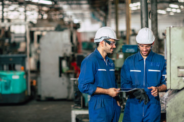 Engineering team in heavy industry factory working together with space for text blue machine...