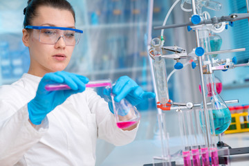 Young woman in chemical lab Young woman in chemical lab. cience professional pipetting solution into the glass cuvette.