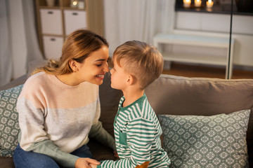 family, love and people concept - happy smiling mother and son touching noses at home in evening