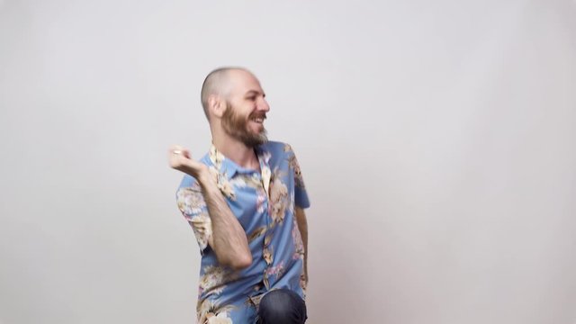 Happy bearded bald man having fun on white background. Joyful lucky tourist wearing hawaiian shirt.