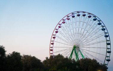 Fototapeta premium Colorful ferris wheel in the city park at evening.