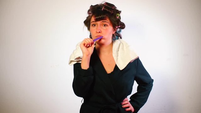 Housewife with curlers on her head brushes her teeth and dances