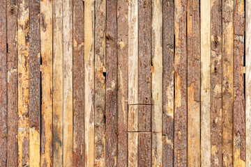 Rustic wood simple wall, with bark and in vertical beams.