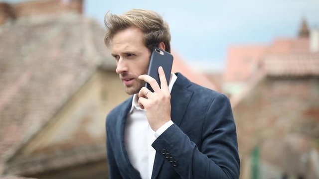young casual man talking on the phone and then looking at the screen to read a new message