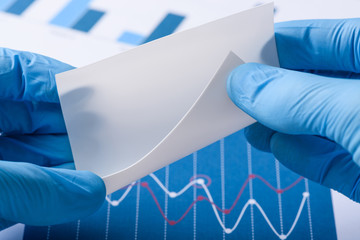 Scientist show white semi transparent sheet of novel flexible material in laboratory