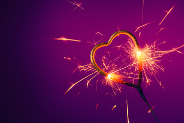 Golden heart shaped sparkler burning bright with sparks