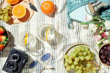 Feminine summer picnic flatlay, fruits, berries and lemon water on striped cotton blanket - obrazy, fototapety, plakaty