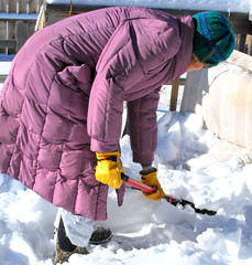 Female shoveling winter snow off patio deck outside.