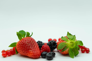 Close up view of strawberries, raspberries, blueberries, blackberries and blackcurrants on a white background. Space for text at the top. Healthy food.