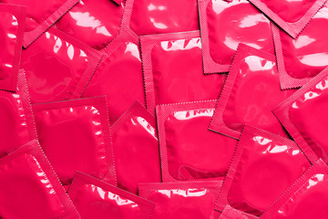 Condoms background top view. Pink foil packaging latex rubber condom backdrop.