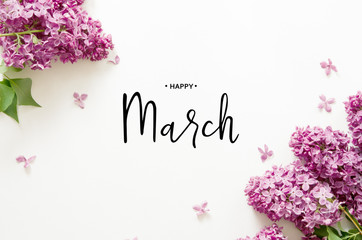 Inscription Happy March. Lilac flowers on white background. Spring flowers. Top view, flat lay. -...