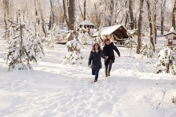 Fototapeta na wymiar Young couple in love running on a snowy winter park