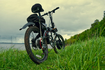 Obraz premium Electric bike on green grass in the background of a natural landscape.