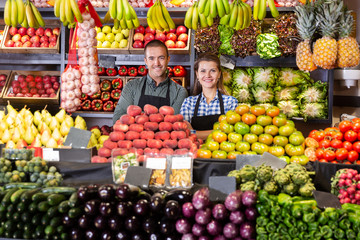 Man and woman sellers standing near vegetables and fruits