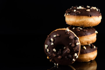 Stack of Chocolate Donuts or Doughnuts on Black Background with Copy Space