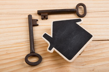 Real estate security,sale or rent concept - little house model and old keys on the wooden background