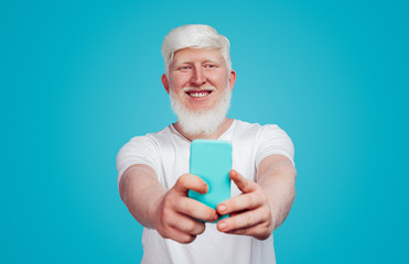 Cheerful albino guy taking selfie in studio
