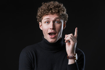 Excited young man wearing turtleneck standing isolated