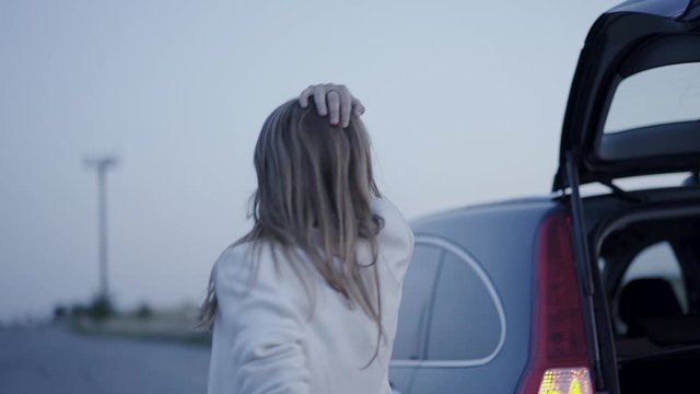 Portrait of worried woman flustering at broken car out of city