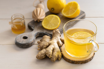 Ginger tea on lemon  on glass mug on light wooden background for help relieve cold and flu symptoms.