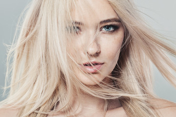 Beautiful blonde woman with long healthy blowing hair and natural skin - obrazy, fototapety, plakaty