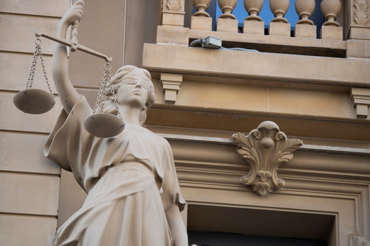 The statue of justice with a scales and a sword in his hand was carved out of stone.