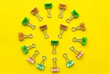 Colorful paperclips lie on yellow background