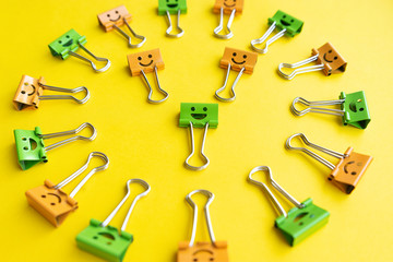 Colorful paperclips lie on yellow background