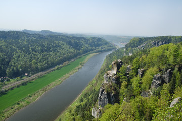Fototapeta na wymiar View on river Elbe from rock formations Bastei in Saxon Switzerland National Park, Germany. Blue sky, springtime.