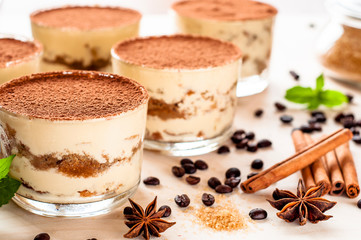 classical tiramisu dessert in a glass sprinkled with cocoa and decorated with coffee beans on a dark background, luxury dessert