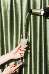 Filling a flute held by girl's hands, with sparkling Prosecco, on a party.