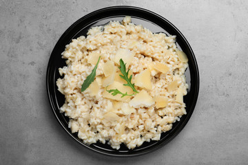 Delicious risotto with cheese on grey table, top view