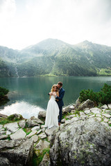 The bride and groom near the lake in the mountains. A couple together against the backdrop of a mountain landscape. Morskie Oko Lake. Tatra mountains in Poland.