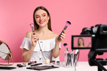 Beauty blogger recording makeup tutorial on pink background
