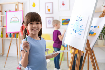 Cute little child painting during lesson in room