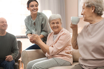Young woman taking care of elderly people in living room