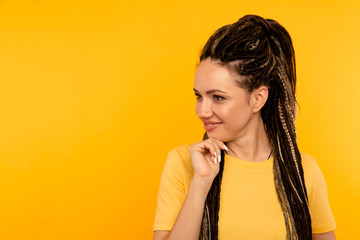 Thinking and posing woman on the yellow studio