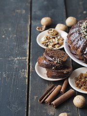 Festive homemade cakes. Round chocolate muffin, large muffin or cake with chocolate icing on a wooden ancient background with nuts and raisins. Place for text.