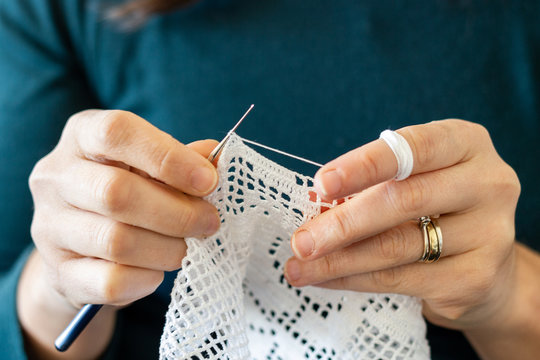 Handcrafted traditional knitting. Woman makes canvas pattern stitches with sewing needle. Cover with thread