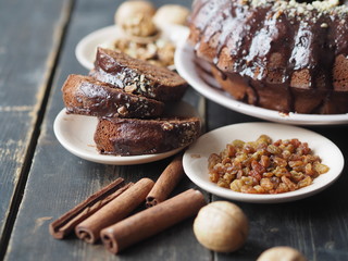 Festive homemade cakes. Round chocolate muffin, large muffin or cake with chocolate icing on a wooden ancient background with nuts and raisins. Place for text.