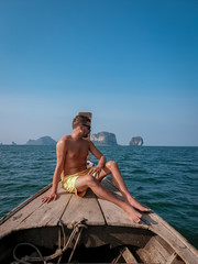 men in swim short on longtail boat in Krabi Thailand, guy on vacation Railay beach Ao Nang krabi