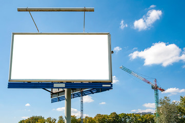 Blank white advertising billboard in front of construction site in the city